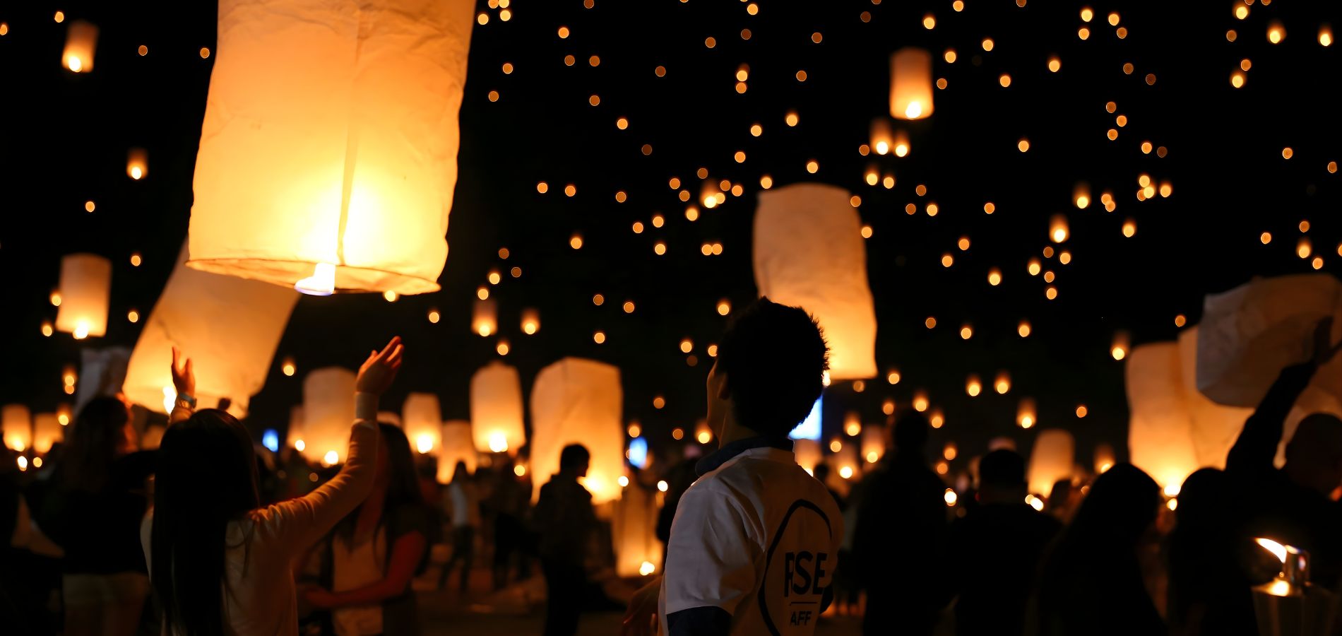 Sky lanterns lighting up the sky during Loy Krathong in Thailand, a traditional festival celebrating light and renewal.